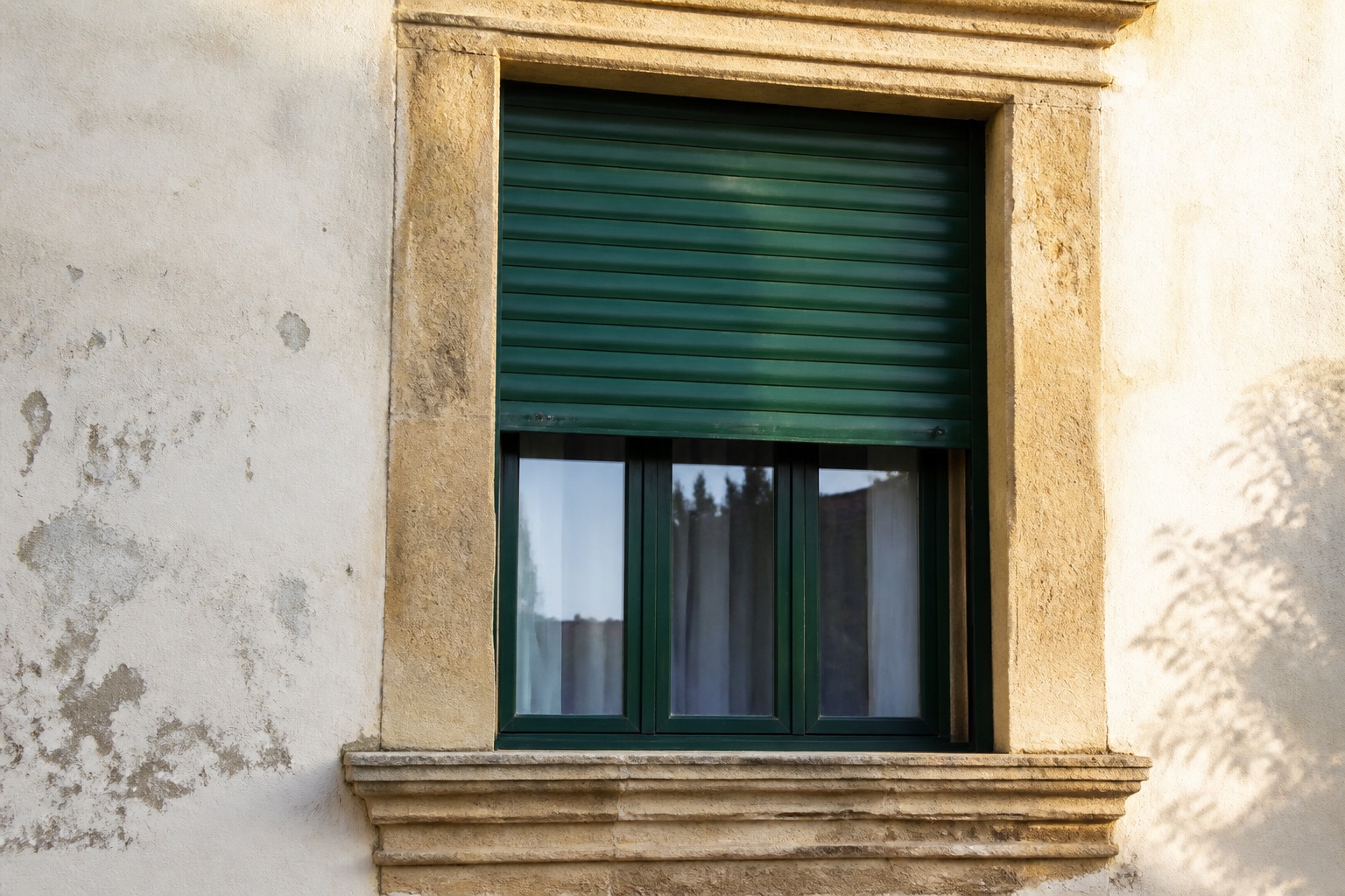 Avvolgibile in legno verniciato verde su una facciata storica